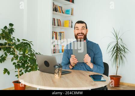 Cheerful handsome bearded man in office showing planner. Stock Photo