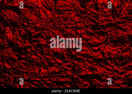 Red foil background with shiny crumpled surface for texture background. Iridescent surface wrinkled foil. Stock Photo
