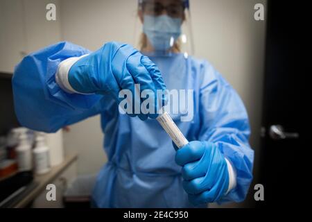 A pharmacist in PPE(personal protective equipment) holds a COVID-19 test in a tube at a pharmacy in Amherstview, Ontario on Friday, January 22, 2021, Stock Photo