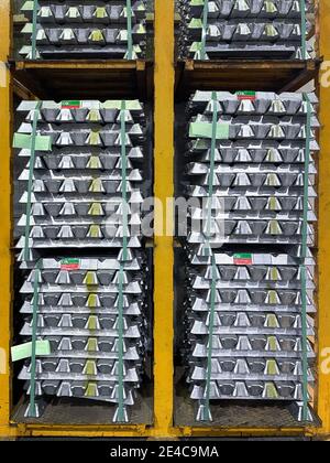 aluminum alloy ingots stacked on a yellow shelf in a warehouse, with quality OK material labels, vertical Stock Photo