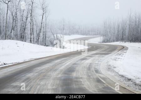 Winding snow covered road through winter forest Stock Photo