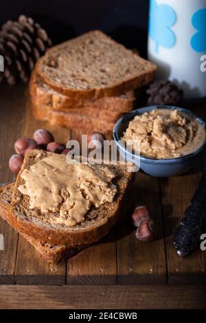 Slices of bread with homemade hazelnut spread and glass of milk on wooden table.  Homemade Hazelnut Butter. Stock Photo