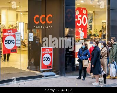 Essen, Ruhr area, North Rhine-Westphalia, Germany - Essen city center in times of the corona crisis during the second part of the lockdown, passers-by with protective masks waiting in front of a shoe store to be admitted, clearance sale due to business closure. Stock Photo