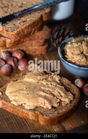 Slices of bread with homemade hazelnut spread and glass of milk on wooden table.  Homemade Hazelnut Butter. Stock Photo