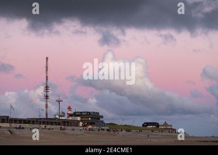 Europe, Germany, Lower Saxony, North Sea, East Frisian Islands, Wadden Sea National Park, Borkum, sunset on the beach with a pink sky, walkers and cyclists on the beach promenade Stock Photo