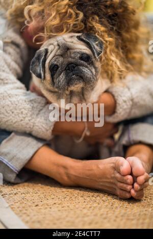 Love and friendship concept with people and animals - happy woman hug her old nice pug at home on the floor - pet therapy healthy lifestyle concept Stock Photo