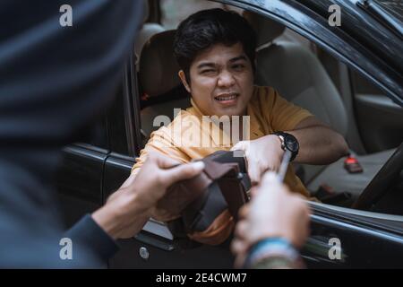 A man grabbed his bag by a thief who used a knife while in a car on the road Stock Photo