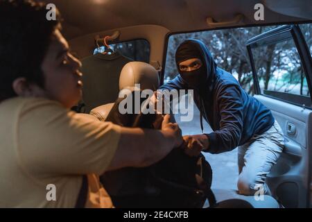 Criminal bandit open car door and with knife force to seize property of victim in the car while on the parking area Stock Photo