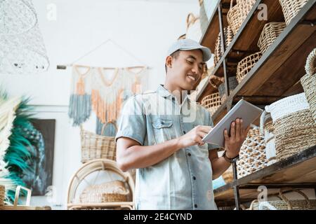 young entrepreneur smiles while holding a digital tablet while standing in a craft shop Stock Photo