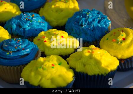 Colorful blue and yellow homemade cupcakes with sprinkles, minion concept party, desserts in blue and yellow color on a table Stock Photo