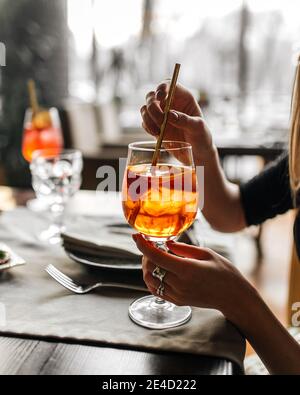 Woman drinking aperol spritz cocktail with a straw Stock Photo