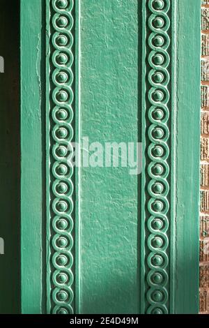 Close up abstract texture background of a vintage textured brown brick wall, surrounded with a decorative green painted wood scrolling design moulding Stock Photo