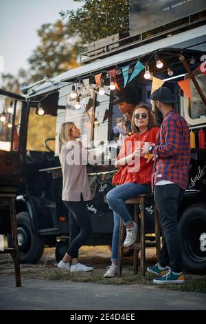 adult people having good time at sunset in front of a truck with food Stock Photo