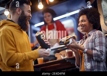 friends having a good time while eating sandwiches in front of fast food service. outdoor Stock Photo