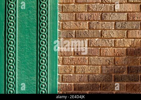 Close up abstract texture background of a vintage textured brown brick wall, surrounded with a decorative green painted wood scrolling design moulding Stock Photo