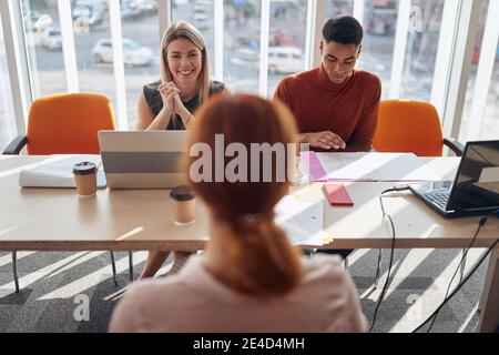 young redhead female at job interview talking with friendly staff Stock Photo