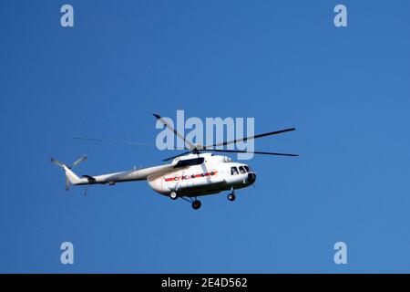 Red rescue helicopter moving in blue sky with blur propeller Stock Photo