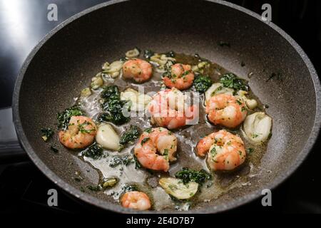 Shrimps or black tiger prawns are sauteed with olive oil, garlic and parsley in a frying pan for a delicious seafood snack, selected focus, narrow dep Stock Photo