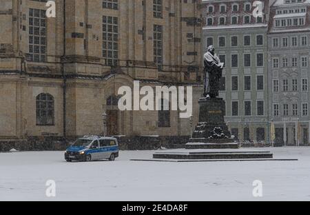 Dresden, Germany. 23rd Jan, 2021. A police car drives along the Martin Luther monument in front of the Frauenkirche on the Neumarkt in the morning during snowfall. Credit: Robert Michael/dpa-Zentralbild/dpa/Alamy Live News Stock Photo