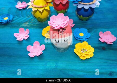 conceptual image if cute Easter egg princess surrounded by paper flowers and other eggs Stock Photo