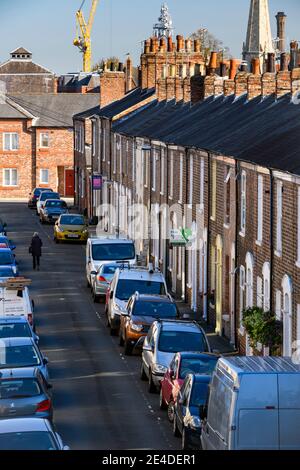 Row of quaint attractive red brick Victorian terraced houses (cottages) & many cars parked on road (parking problem) - Bishophill, York, England, UK. Stock Photo