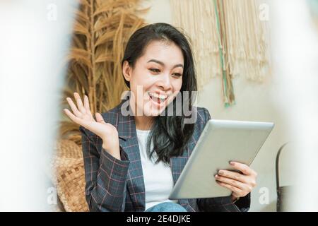a happy beautiful woman in a blazer uses a digital tablet with a background in many crafts Stock Photo