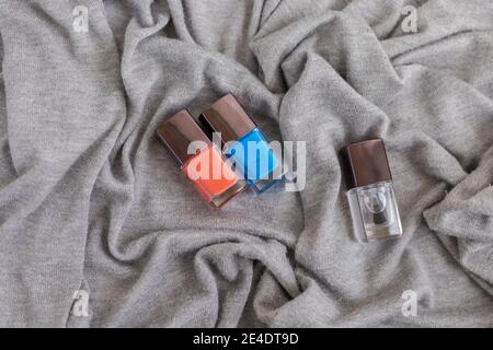 Collection of multi-colored bottles of nail polish. Layout for design on a gray background and a wooden table. Stock Photo