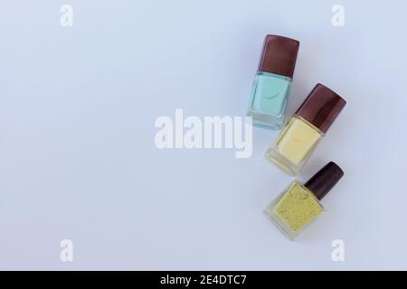 Collection of multi-colored bottles of nail polish. Layout for design on a gray background and a wooden table. Stock Photo