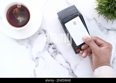 man's hand making contactless payment with credit card on face table  Stock Photo