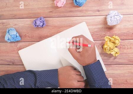 crumpled paper ball and notepad on wooden table. Stock Photo