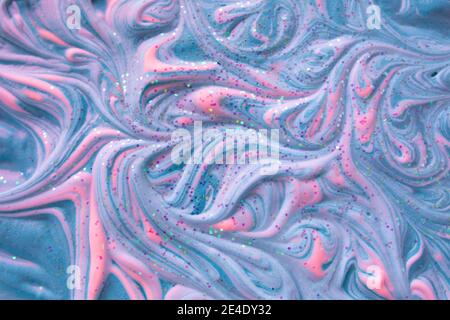 Liquid smooth fluid art background at pastel blue and creamy pink colors. Volume relief of colorful foam with glitter. Acrylic ink foam. Creative tren Stock Photo