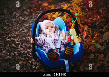 Little girl in car seat in autumn park Stock Photo