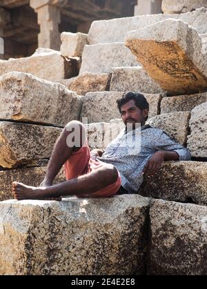 hampi, Karnataka, India- November 10,2020 : Man sitting on boulder stone Stock Photo