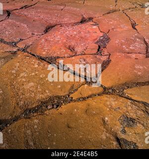 Colorful volcanic rocks with red and turquoise volcano soil with cracks and patterns as background Stock Photo