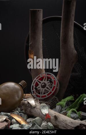 Fishing reel and iron baubles on a background of stones and wood. Vertical frame. Stock Photo