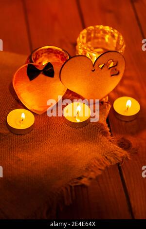 Two hearts and candles on wooden boards. St Valentine's day greeting card with candles and hearts on a blurred background. Love story concept Stock Photo