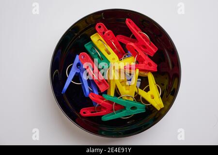 Multicolor laundry clips on black bowl on white background Stock Photo