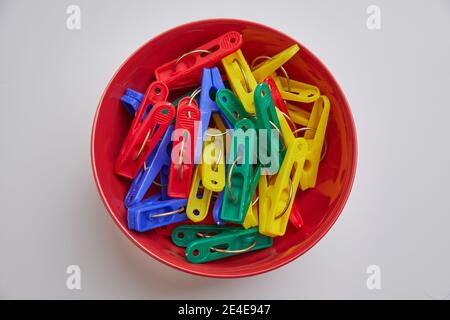 Top view of colorful laundry clips on red bowl Stock Photo