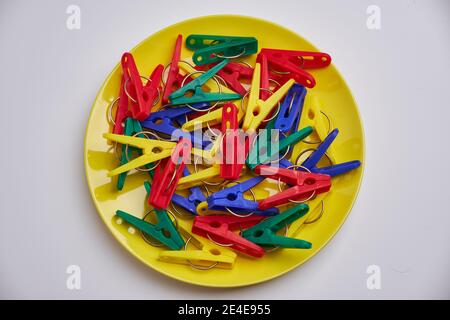 Multicolor laundry clips on yellow plate Stock Photo