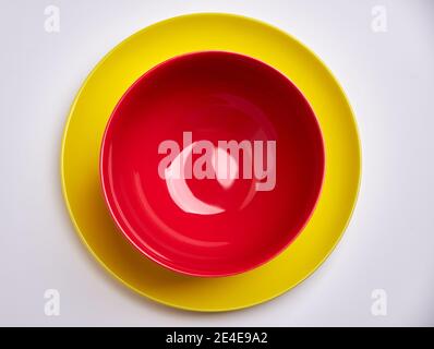 Empty red bowl on yellow plate with white background Stock Photo