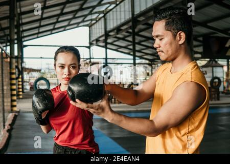 Trainer with a woman boxer standing together during a training Stock Photo