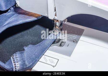 Sewing machine foot on denim, hem hemming Stock Photo