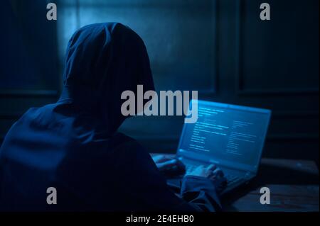 A Hacker is using laptop computer to steal data in the night Stock Photo
