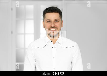 Happy smiling young Hispanic businessman standing in office looking at camera. Copyspace or copy space next to business professional with smile on his Stock Photo