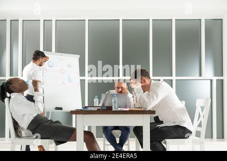 Brainstorm concept. Group of international partners are discussing the project for a long time and looking very tired Stock Photo