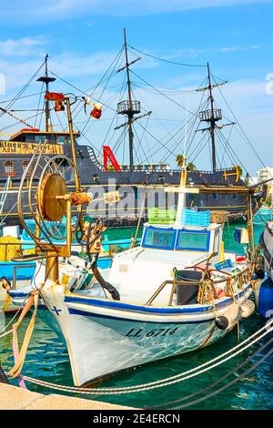 Aya Napa, Cyprus - January 24, 2019: Fishing boats and big tourist sail ship in the port of Ayia Napa Stock Photo