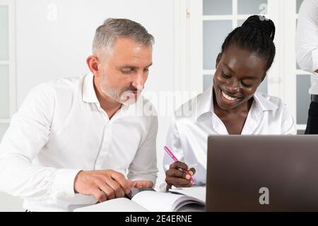 Two business partners, young african woman and senior caucasian man, working with new ideas about project in conference Stock Photo