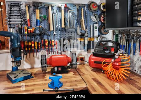 A collection of assorted tools hanging on the wall with a work bench Stock Photo
