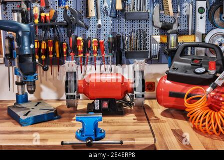 A collection of assorted tools hanging on the wall with a work bench Stock Photo