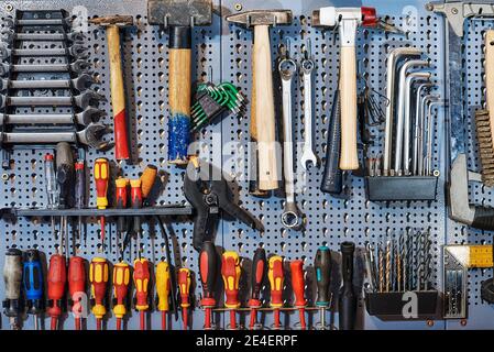 A collection of assorted tools hanging on the wall with a work bench Stock Photo
